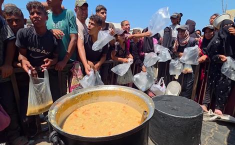 نازحون ينتظرون لساعات للحصول على طعام من مطبخ خيري بمنطقة المواصي في خان يونس جنوب قطاع غزة